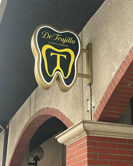 Cartel luminoso de la clínica con forma de diente y la letra T, junto a los arcos de ladrillo