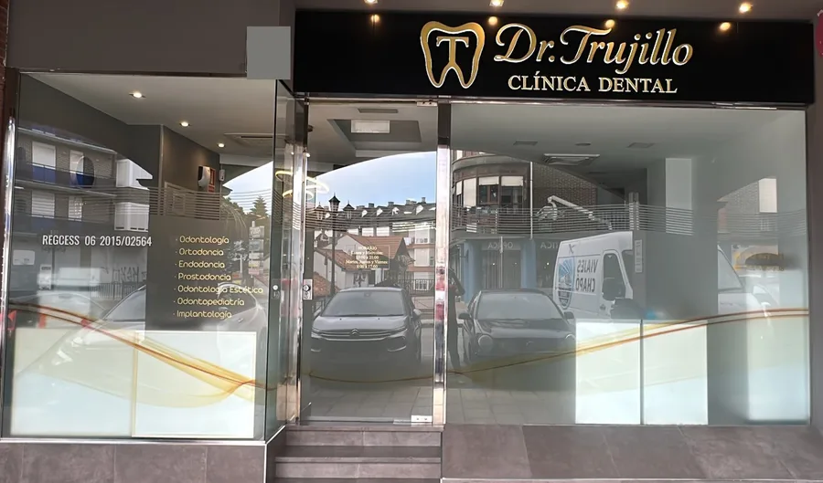 Fachada de la clínica dental Dr. Trujillo: puerta de cristal y rótulo dorado sobre fondo negro